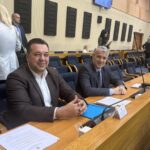 Zabrinuta medicinska sestra drži stetoskop u praznom bolničkom hodniku, ilustrujući problem malih plata i odlaska kadra u inostranstvo.