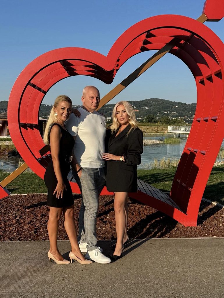Tim emisije "Stil": Voditeljice Jelena Matošević i Neda Gavrić, te producent Jakša, snimljeni ispred crvene skulpture srca u parku.
